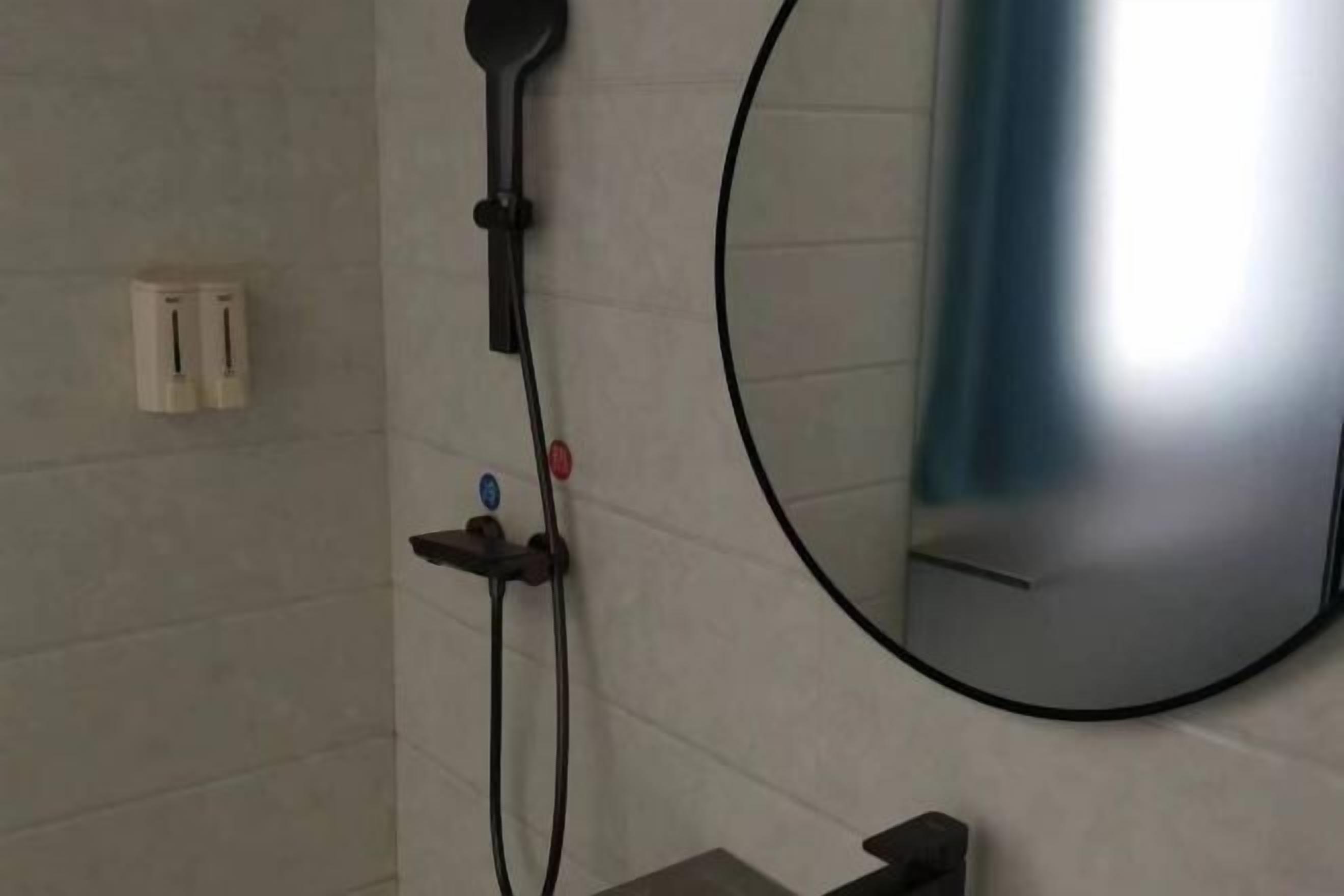 Un baño con ducha, espejo y toallero.