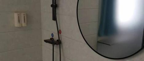 Un baño con ducha, espejo y toallero.