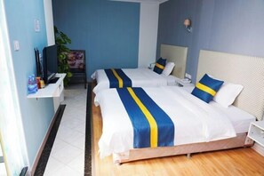 Een hotelkamer met twee bedden, een televisie, een bureau en een plant.