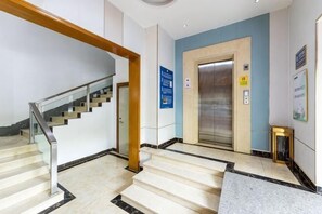 A hotel lobby with a staircase, an elevator, and a reception desk. - Impression Hotel (Zhuhai)