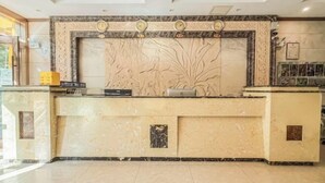 Una recepción con mostrador de mármol, un reloj y un panel decorativo en la pared.
