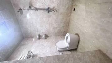A bathroom with a shower, a toilet, and a towel rack.