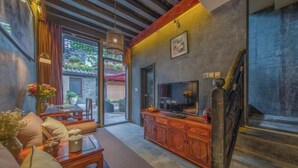 A modern interior with a sofa, coffee table, TV, and a staircase. - Ten Courtyard Inn (Lijiang)