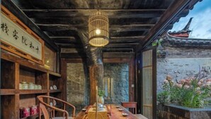 A traditional wooden dining table with a hanging light fixture, surrounded by wooden chairs. - Ten Courtyard Inn (Lijiang)