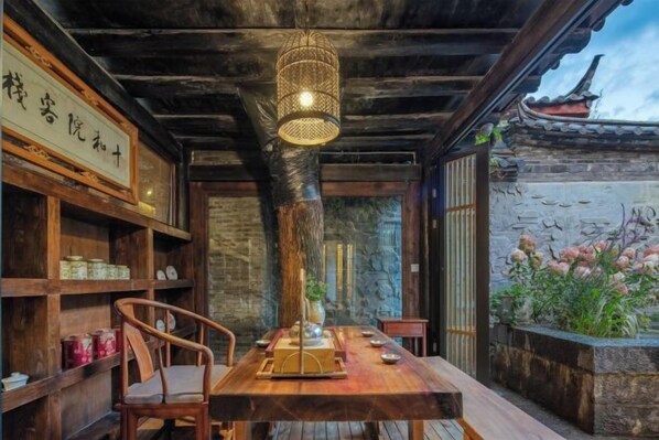 A traditional wooden dining table with a hanging light fixture, surrounded by wooden chairs. - Ten Courtyard Inn (Lijiang)