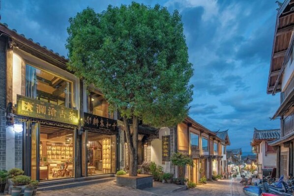 A traditional street with buildings, a tree, and a clear sky.