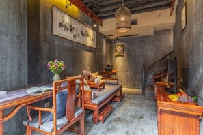 A room with a long wooden table, cushioned seating, a staircase, and a fruit basket.
