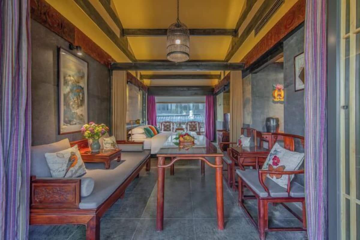 A spacious room with a sofa set, wooden chairs, a coffee table, and a hanging light fixture.