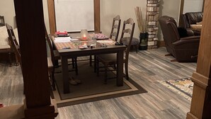 A dining area with a wooden table, chairs, a chandelier, and a stone accent wall. - Downtown Des Moines (Des Moines)