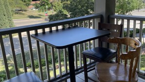A balcony with a table and two chairs, overlooking a parking lot and buildings. - Downtown Des Moines (Des Moines)
