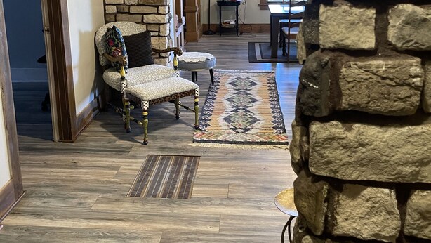 A stone archway leading to a living area with a patterned rug, a patterned armchair, and a floor lamp. - Downtown Des Moines (Des Moines)
