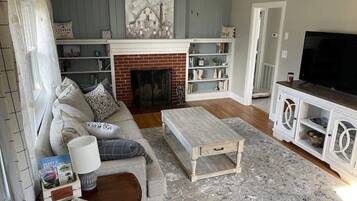 A living room with a fireplace, a sofa, a coffee table, and a TV.