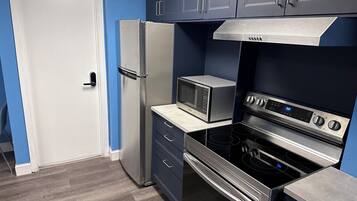 A compact kitchen with a refrigerator, microwave, oven, and stove.