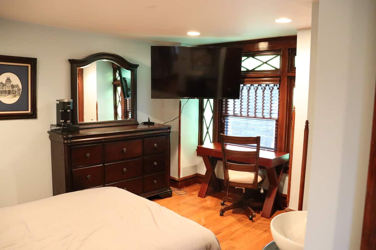 Une chambre à coucher comprenant un lit, une commode, un bureau, une chaise et un téléviseur.