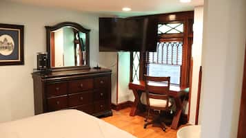 Een slaapkamer met een bed, een dressoir, een bureau, een stoel en een televisie.