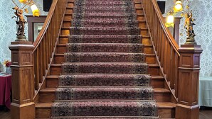 Eine prächtige Treppe mit aufwendiger Geländerarbeiten und einem gemusterten Teppich.