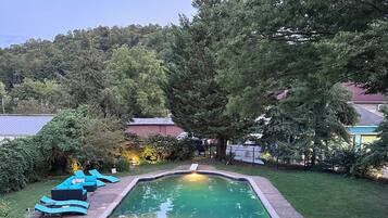 A backyard with a swimming pool, surrounded by a well-maintained lawn and trees.