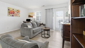 A modern living room with a grey sofa, a small round table, and a bookshelf. - Spacious 2 bedrooms townhouse by the Greenway/ Pool access (Raleigh)