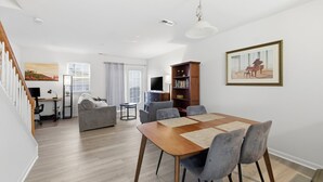 A modern living room with a dining area, a sofa, a TV, and a bookshelf. - Spacious 2 bedrooms townhouse by the Greenway/ Pool access (Raleigh)