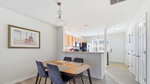 A modern kitchen with wooden cabinets, a central island, and a dining area with a wooden table and chairs. - Spacious 2 bedrooms townhouse by the Greenway/ Pool access (Raleigh)