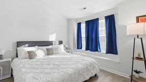 A bedroom with a bed, a nightstand, a lamp, a window with curtains, and a floor lamp. - Spacious 2 bedrooms townhouse by the Greenway/ Pool access (Raleigh)