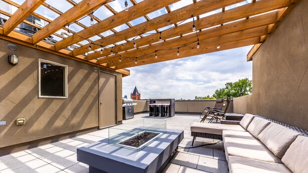 An outdoor patio with a wooden pergola, a glass-top table, and a sofa. - Post-Worthy Rooftop Views / Super Walkable LoHi Area / Modern 3b3b (Denver)