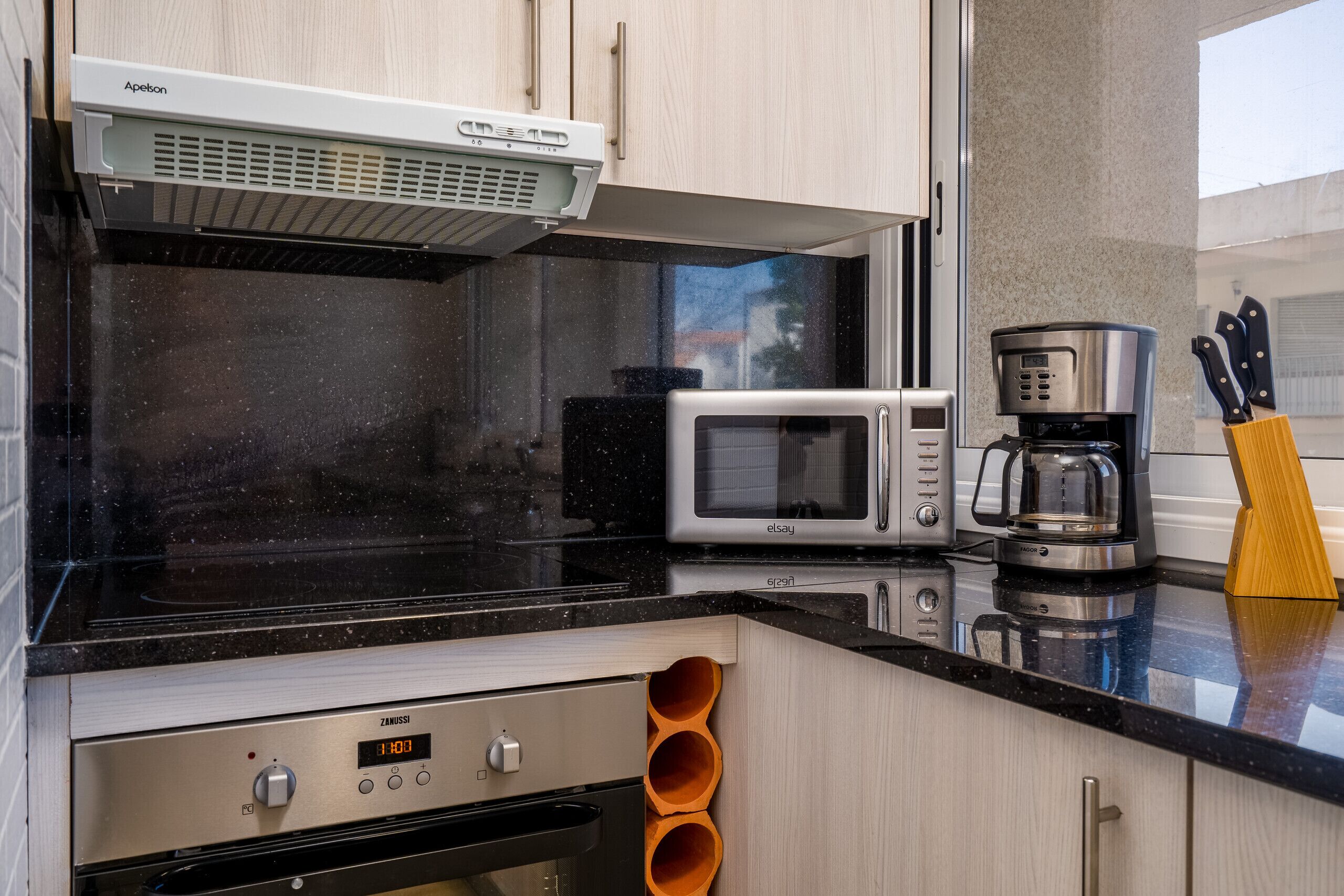 A modern kitchen with a built-in microwave, coffee maker, and oven.