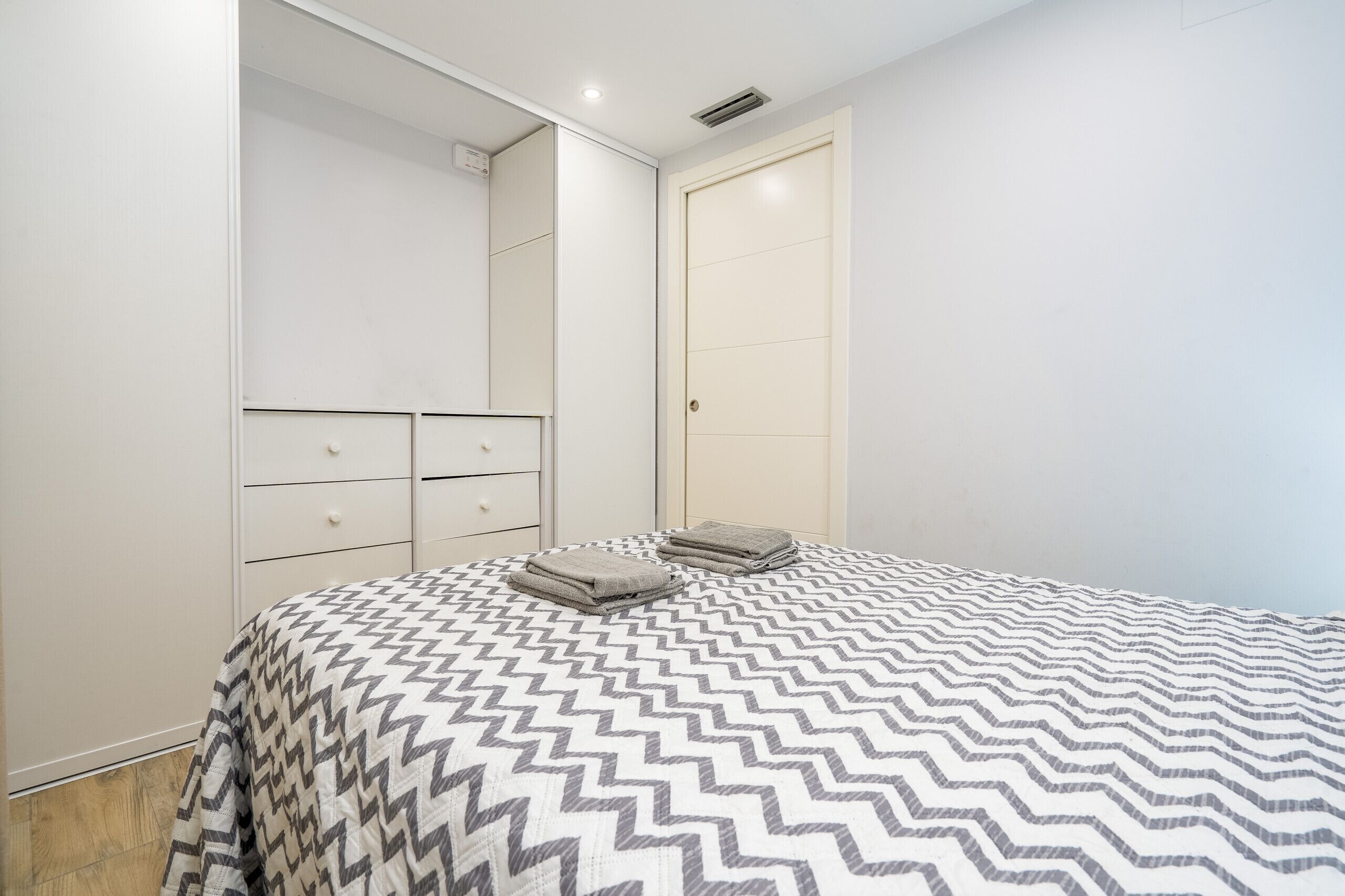 A bedroom with a bed, a wardrobe, and a door.