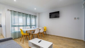 A modern living room with a sofa, a coffee table, and a dining area with chairs. - WELCS APARTAMENTO 027 EMP en el puerto de Roses (Rosas / Roses)