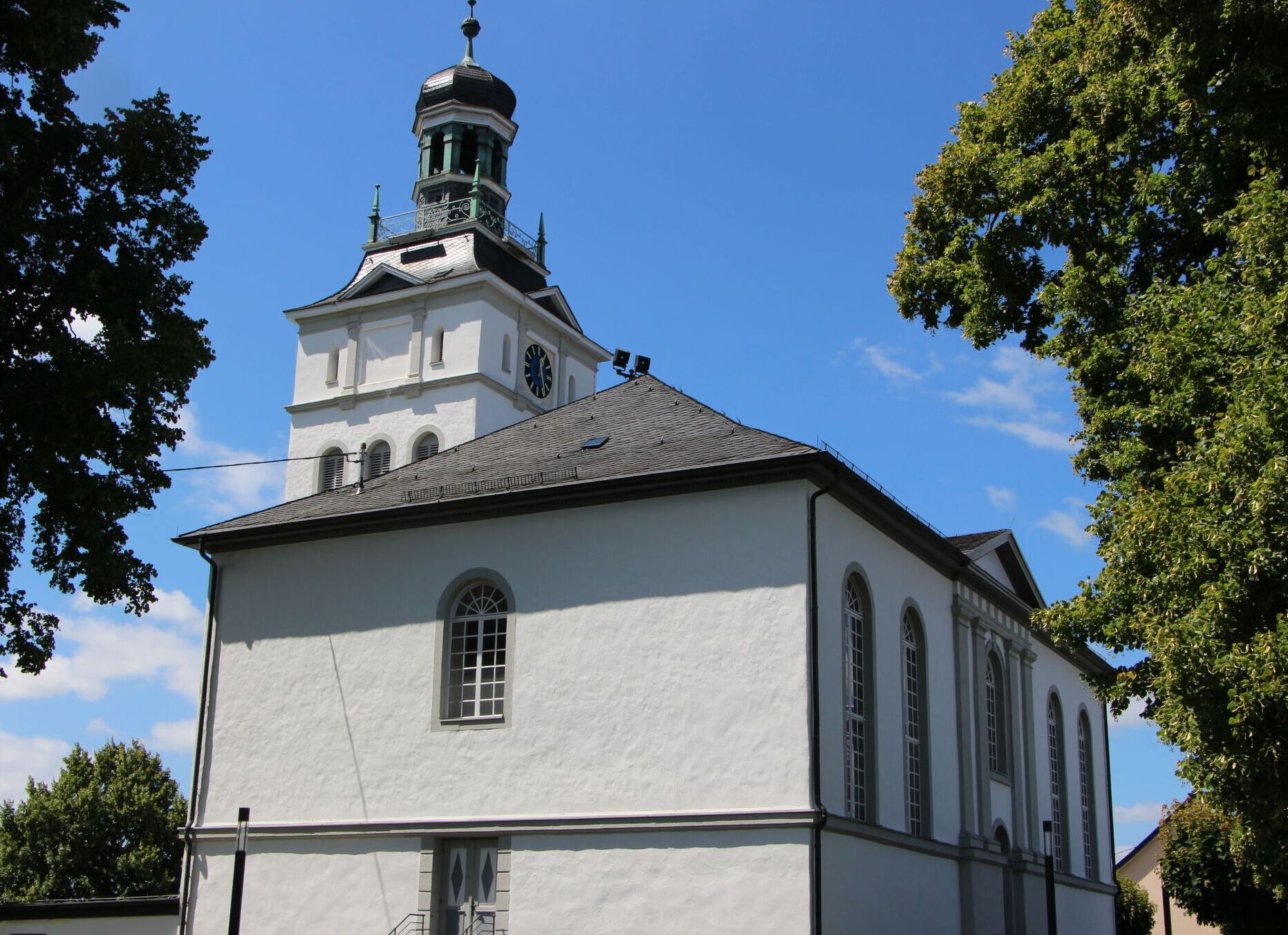 Una iglesia blanca con una torre de reloj y un campanario.