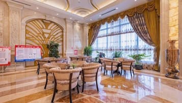 Un hall espacioso con piso de mármol pulido, elegantes sillas y ventanas grandes con cortinas.