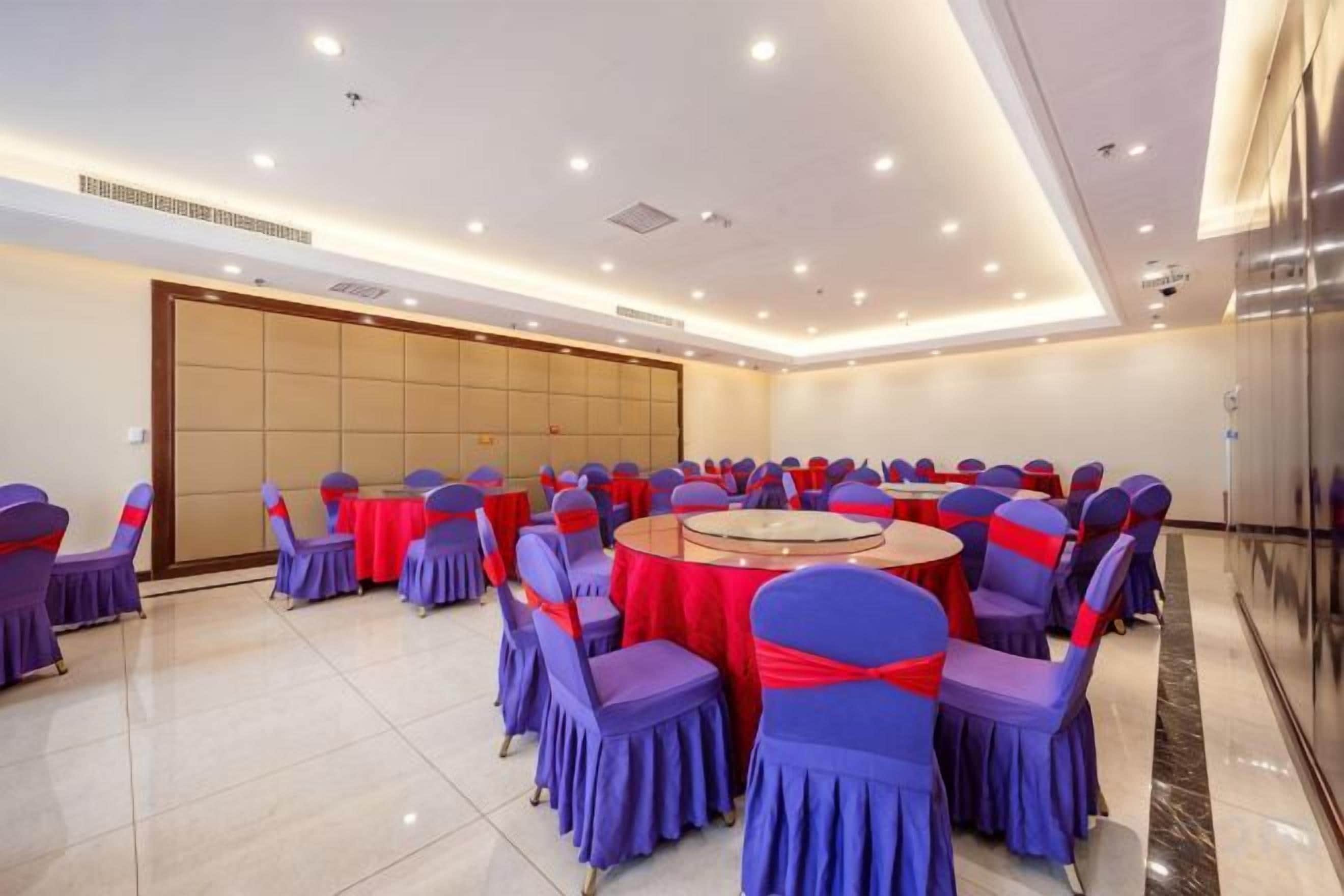 Une salle de conférence avec des tables et des chaises rondes, une grande porte et un sol carrelé.
