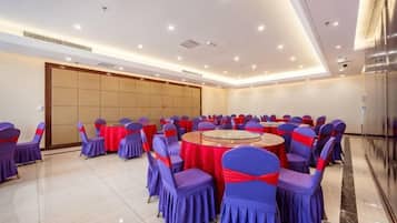 Une salle de conférence avec des tables et des chaises rondes, une grande porte et un sol carrelé.