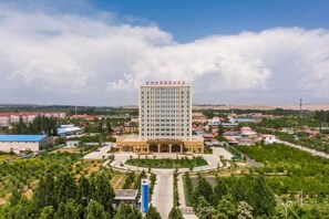 A large hotel with multiple floors, a central courtyard, and a surrounding landscaped area.