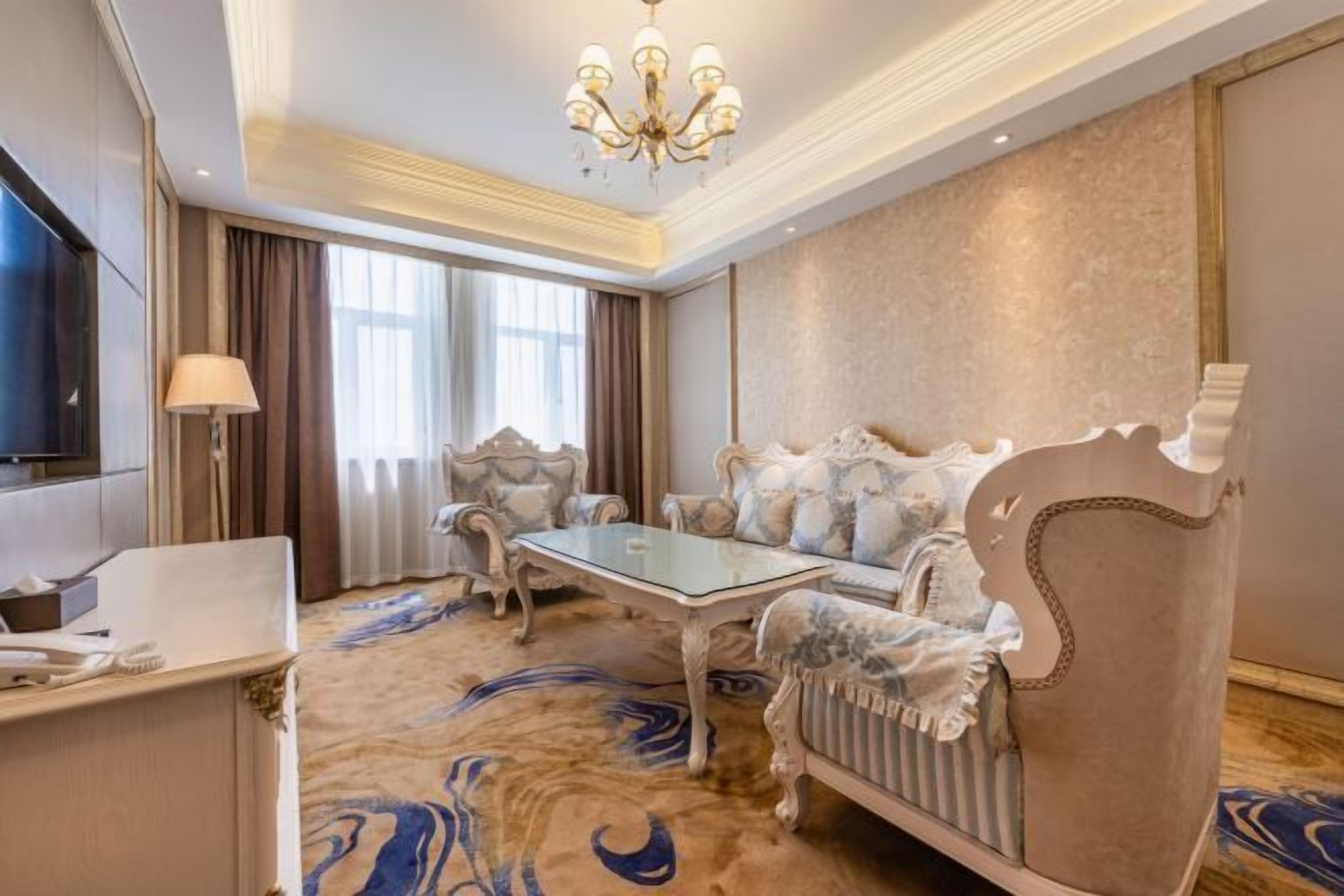 A luxurious room with a plush sofa, a glass coffee table, and a TV.