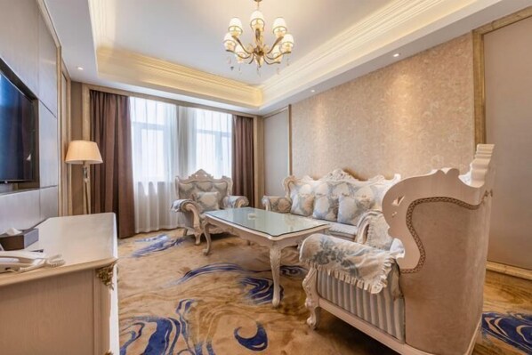 A luxurious room with a plush sofa, a glass coffee table, and a TV.