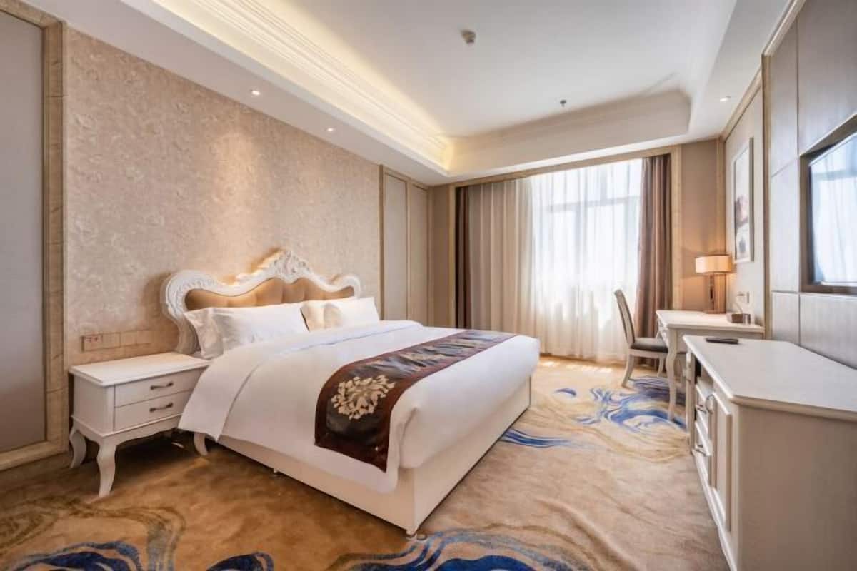Una habitación de hotel con una cama grande, un escritorio y una silla.