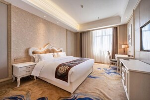 Una habitación de hotel con una cama grande, un escritorio y una silla.