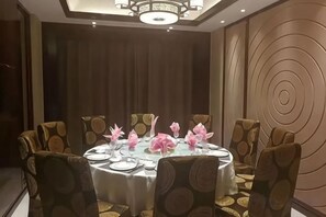 A round table with chairs, a chandelier, and a wall with circular patterns. - Jinze Ali Mali Hotel (Khorgas)