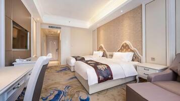 Ein Hotelzimmer mit Bett, Schreibtisch, Stuhl und Fernseher.