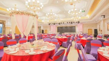 Une salle de banquet avec des tables rondes, des chaises et une scène.