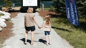 A gravel path with a banner reading "Welcome to the HIDEAWAY". - The Hideaway at Glacier Meadows - Luxury Camper (Martin City)