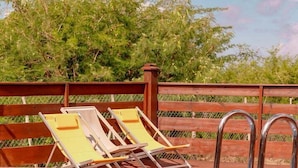 A swimming pool with a wooden deck and metal ladder, surrounded by a wooden fence and trees. - TIPI 2 Kalbas • Domaine de Meilly (Saint-Louis)