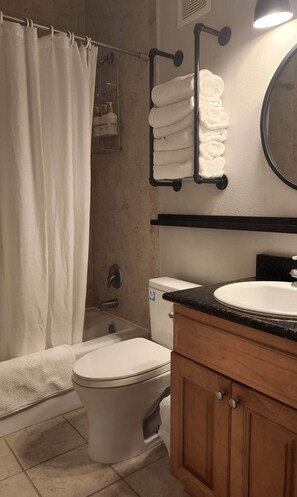 Un baño con inodoro, lavamanos y zona de ducha.