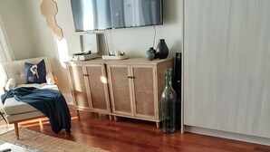 Un salon comprenant un canapé, une table basse, un téléviseur et un meuble.