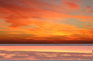 Un atardecer sobre un paisaje costero con horizonte despejado.