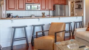 Une cuisine moderne avec des meubles en bois, un réfrigérateur en acier inoxydable et un coin bar équipé de tabourets.