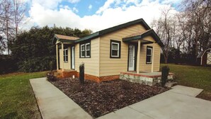 A single-story house with a gabled roof, a front porch, and a small front yard with mulch.