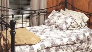 A bed with a metal frame, a patterned bedspread, and a tan throw pillow.