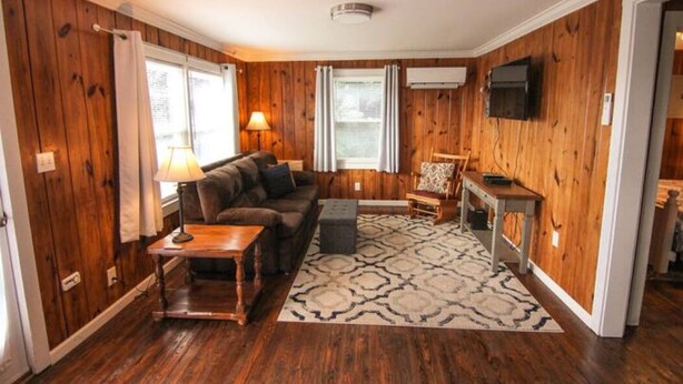 A cozy living room with wooden walls, a sofa, a coffee table, and a patterned rug.